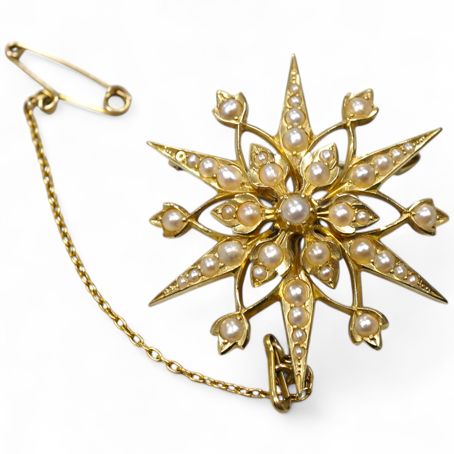 An Edwardian seed pearl brooch, early 20th century, designed as a snowflake, set with split seed pearls, mounted in gold, length 3.7cm, stamped 15CT, pearls untested, Condition: good, minor wear